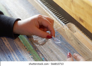Hands of a woman when weaving a blue and white rag carpet in the loom