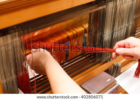 Hands of a woman who weaves on a loom