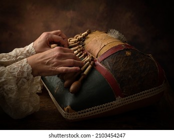 Hands of a woman working on an antique Flemish lace making pillow