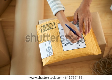 Hands of woman writing address on first class mail package