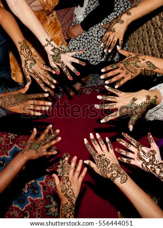 The hands of women during a henner tattoo session before the traditional wedding celebration