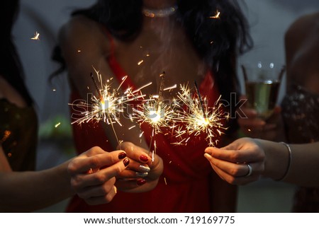 Hands of women holding Bengal light at the party
