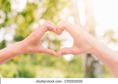 The hands of women and men are the heart shape with the sun light passing through the hands - Shutterstock ID 1703310550