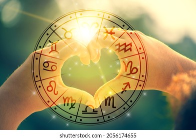 The hands of women and men are the heart shape with the sun light passing through the hands have astrological symbols - Shutterstock ID 2056174655