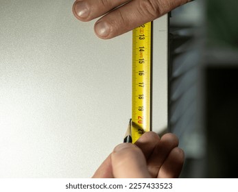 Hands woodworker measuring with tape and wiriting down on wooden board with pencil, concept of carpenter craftsman in his workshop
