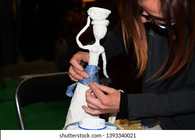 Hands At Work, Creating A Thin And Modern Papier-mâché Doll, Applying Purple Details With Glue And Paper.