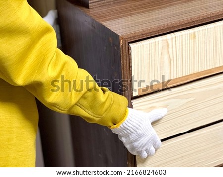 Hands with work gloves to move old chest of drawers
