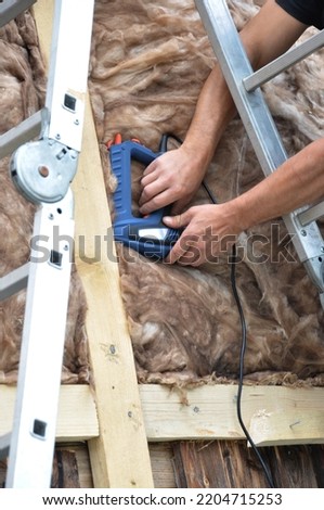 
hands of worker attaching insulation material with a stapler