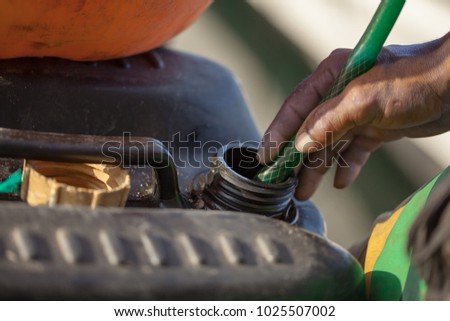 Hands of a worker holding a hose that drives gasoline to a fuel container, fuel smuggling, illegal extraction at the border, South America.