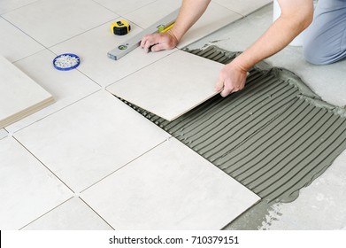 The Hands Of The Worker Are Laying  The Ceramic Tile On The Floor.