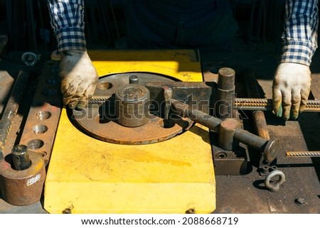 Hands of a worker at work at the armature bending machine. Rebars with rebar bending machine in the site. Worker using bending rebar machine for reinforcement in the construction work