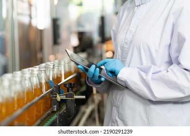 Hands of worker working with digital tablet check product on the conveyor belt in the beverage factory. Worker checking bottling line for processing. Inspection quality control - Powered by Shutterstock