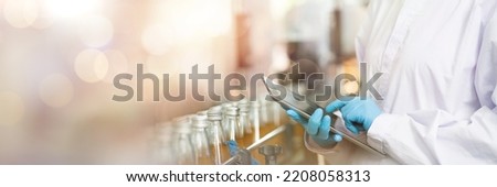 Hands of worker working with digital tablet check product on the conveyor belt in the beverage factory. Worker checking bottling line for processing. Inspection quality control