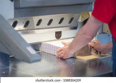 Hands of worker working on cutter guillotine machine in a printing factory