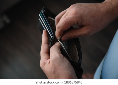 the hands of a working man put one dollar bills in an empty wallet. Poverty concept, crisis. firing or saving money