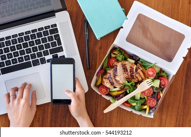 Hands working on laptop computer and ordering food on mobile cell phone app application