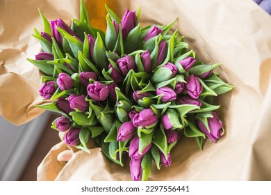 Hands wrapping purple tulips bouquet in craft paper , happy mothers day,valentines gift. Greeting card with tulips. Spring flowers in eco paper. beautiful and eco frendly.Mother's day - Powered by Shutterstock