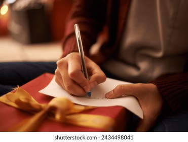 Hands, writing letter and Christmas in home with box, present and message with festive wish in closeup. Person, pen and paper with notes, gift and package with kindness, celebration and xmas card - Powered by Shutterstock