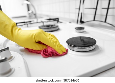 Hands in yellow gloves washing the gas stove.