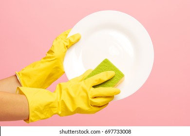 Hands in yellow protective gloves washing a plate