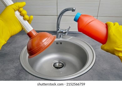 Hands in yellow rubber gloves hold a plunger and pipe cleaner against the backdrop of a kitchen sink. Drain clog cleaning work