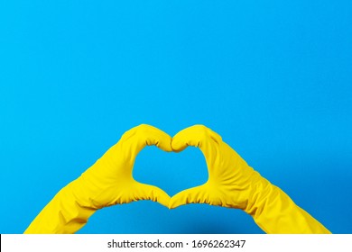 Hands In Yellow Rubber Gloves Making Heart Shape With Fingers, On Blue Background