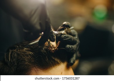 The Hands Of Young Barber Making Haircut To Attractive Man In Barbershop. Mens Hair Cutting Scissors In A Beauty Salon. Haircut Of The Boy In The Barbershop. Men's Haircut At The Barber Scissors