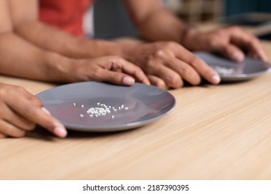 Hands Of Young Black Family Hold Plates With Some Grains Of Rice At Table In Kitchen, Cropped. Diet, Meal Crisis, Hunger And Poverty. Global Food Scarcity, Eat Shortage And Supply Chain Problems