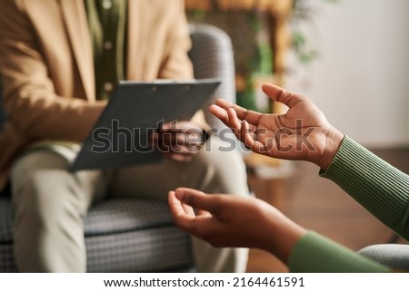 Hands of young black woman describing her mental problem to counselor sitting in front of her during psychological session