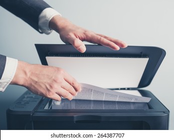 The Hands Of A Young Businessman Is Placing A Document On A Flatbed Scanner In Preparation For Copying It