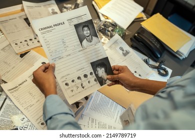 Hands Of Young Female FBI Agent Holding Document With Personal Data Of Criminal During Investigation Assignment In Office