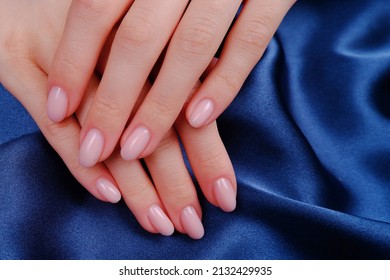 The hands of a young girl on a blue silk fabric, pink nail polish.The concept of hand care, manicure, beauty salon, cosmetics for hand care.Place for text - Powered by Shutterstock