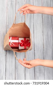 Hands Of A Young Girl Open A Paper Bag Full Of Gifts.