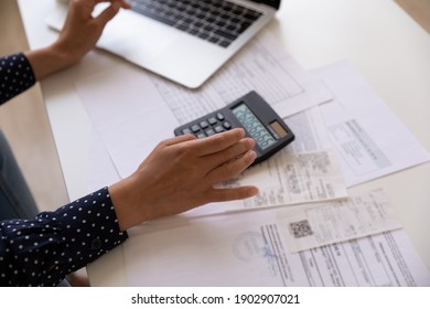 Hands of young lady planning financial charges costs at home office using laptop calculator. Cropped shot of woman making audit of paying utilities calculating income checking paper invoices. Close up - Shutterstock ID 1902907021