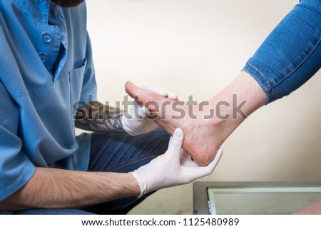 The hands of a young man doctor orthopedist conducts diagnostics, foot foot test of a woman, for the manufacture of individual, orthopedic insoles.