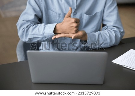 Hands of young man with hearing disability talking on video call with hand signs, showing gestures at laptop display, webcam, using service, smart application for patient with deafness. Cropped shot