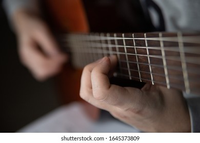 hands of a young man playing on a classical guitar