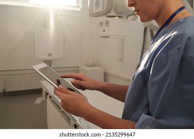 Hands Of Young Modern Female Clinician Pointing At Tablet Screen While Searching For Online List Of Patients In Radiologist Office