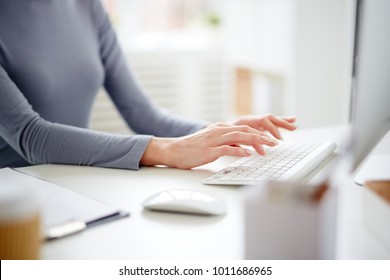 Hands of young secretary over computer keyboard typing by workplace