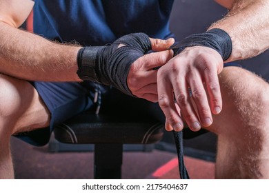 Hands Of Young And Strong Mixed Martial Arts Fighter Who Wraps Black Protective Elastic Bandage Around His Fists