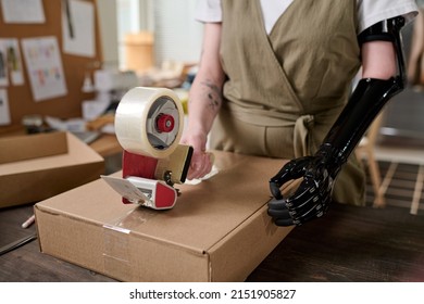 Hands of young warehouse worker with myoelectric arm sealing box with cellotape