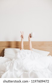 Hand's Of Young Woman With Coffee Mug In Bed With White Linens. Minimal Happy Morning Concept.