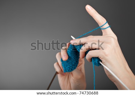 Hands of a young woman knitting with blue wool