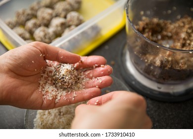 The Hands Of A Young Woman Make Delicious Organic Sweets. Girl Prepares Protein Balls From Raw Nuts, Coconut, Dates And Cocoa. Healthy Eating Concept