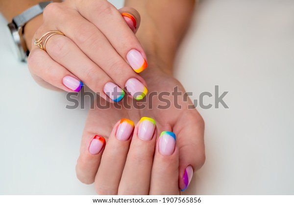 Hands of a young woman with a\
manicure. The nails are covered with gel polish with colored\
French.