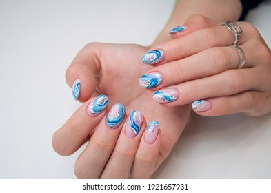 Hands of a young woman. The nails are covered with a light colored gel Polish with a bright design. Manicure ideas.