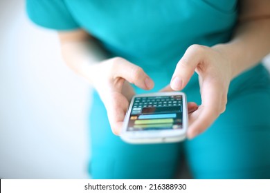 Hands of young woman sending text message from smart phone at work
