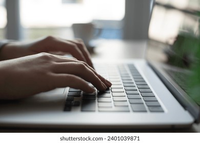 Hands of young woman typing on laptop when working at office desk at home