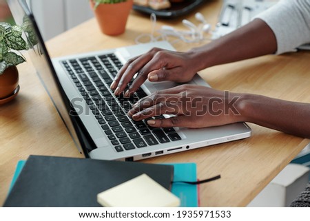 Hands of young woman typing on laptop when working at office desk at home