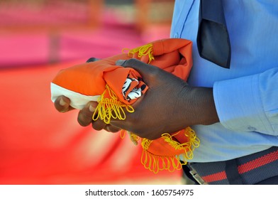 Hands Of A Zambian Police Officer Holding The Folded Orange Flag Of The President Of Zambia 